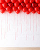 Red heart-shaped balloons arranged in a pattern on a white background